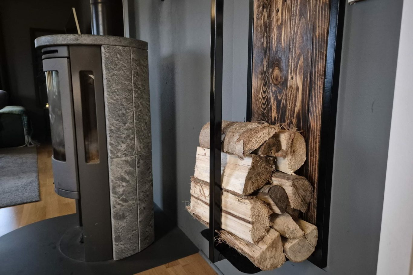 Vedstapel Mörk steneldstad med vedstapel i modern inredning.